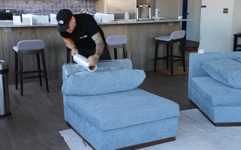 A Flatrate mover wrapping a sofa with plastic for protection during the move