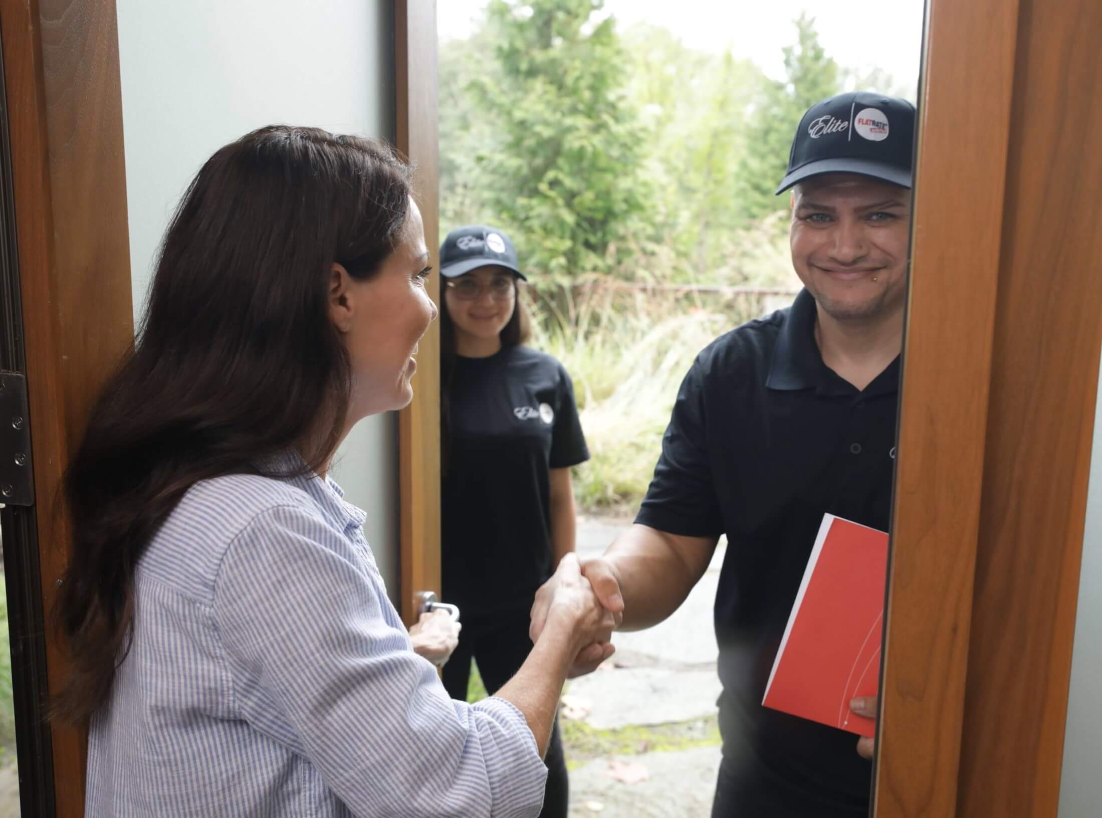 Flatrate mover shaking hands with a satisfied customer in front of her home's front door