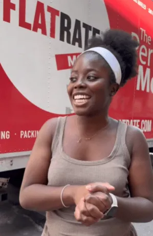 Smiling customer standing in front of Flat Rate moving truck.